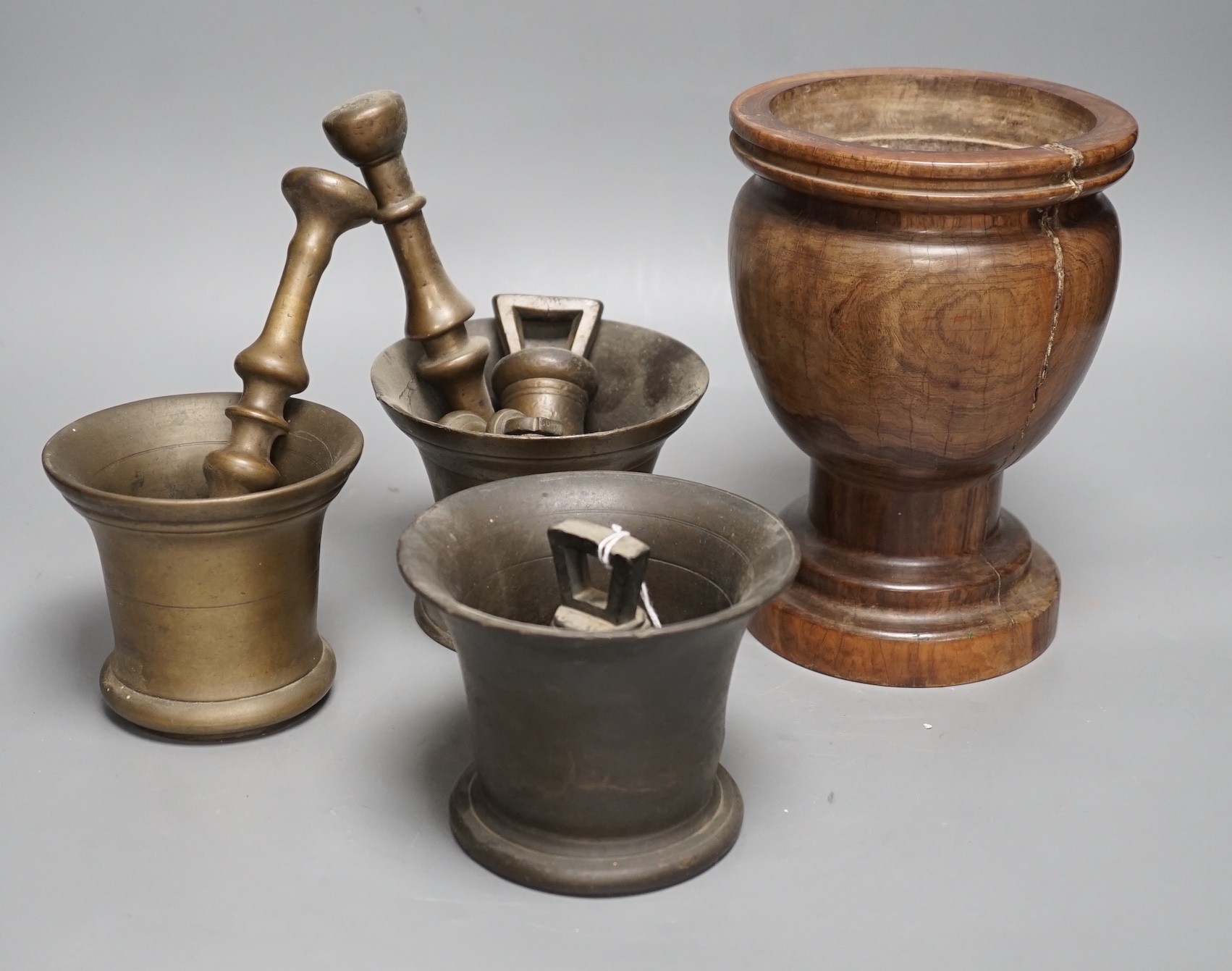 Three bell metal mortars, two pestles, a turned lignum vitae mortar and three postal weights, urn height 20cm